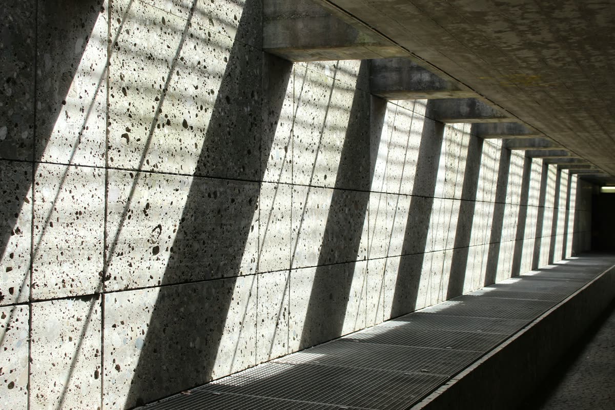 Parede de concreto cortada por faixas diagonais de luz e sombra