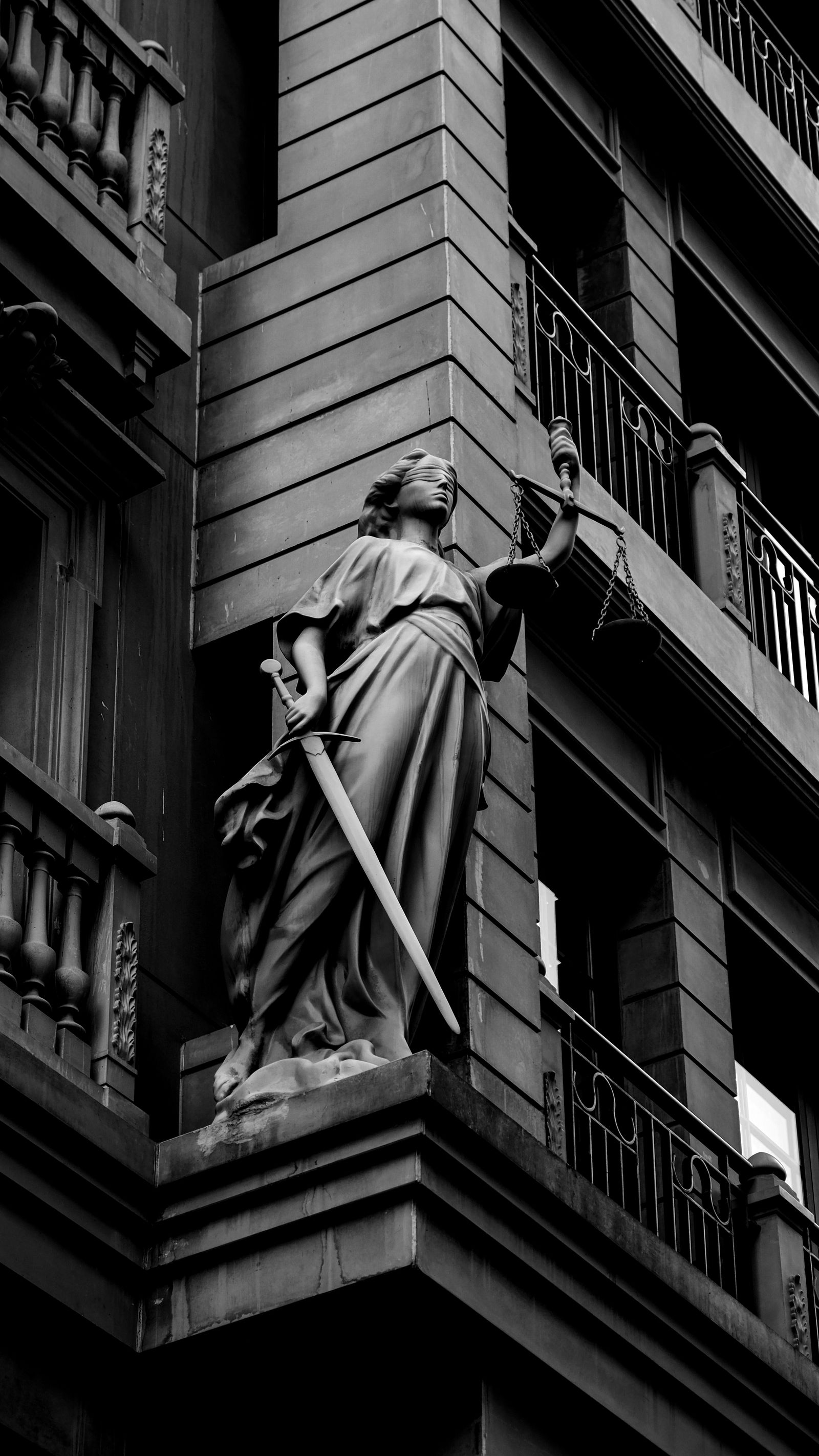 Estátua da Justiça, de olhos vendados, na fachada de um prédio antigo